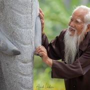 Vieil homme posant devant une statue d'éléphant